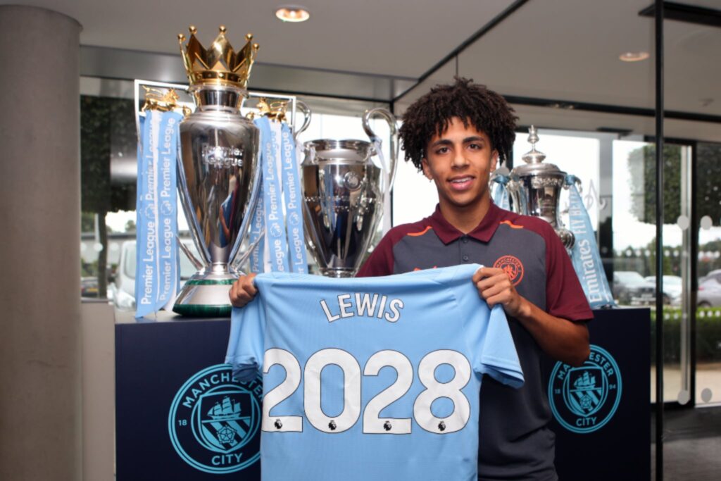 Rico Lewis - Man City contract until 2028, pictured in front of the Treble trophies - Premier League, FA Cup, and Champions League